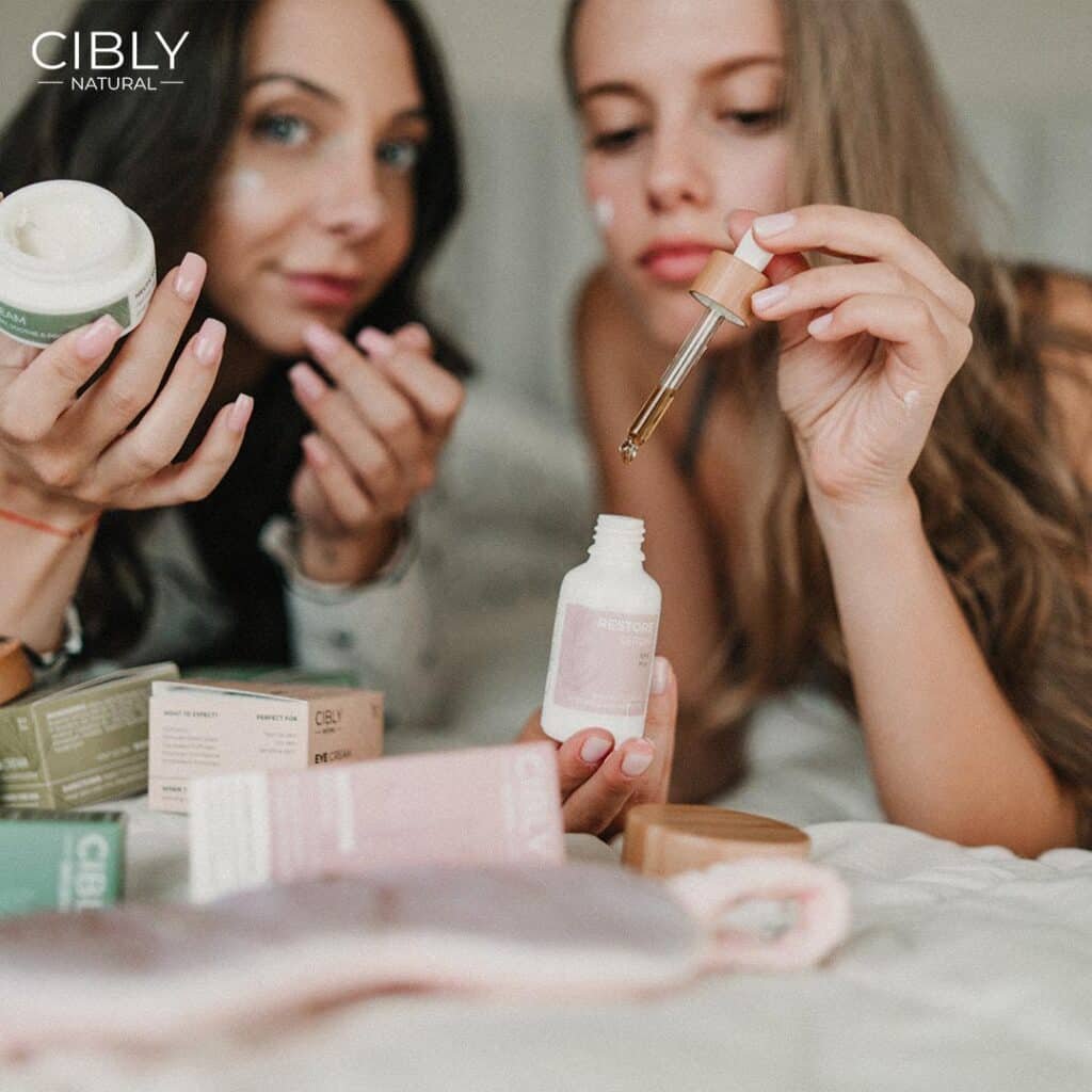 Две млади жени изпробват козметични продукти на Cibly, заобиколени от натурални кремове и серуми.