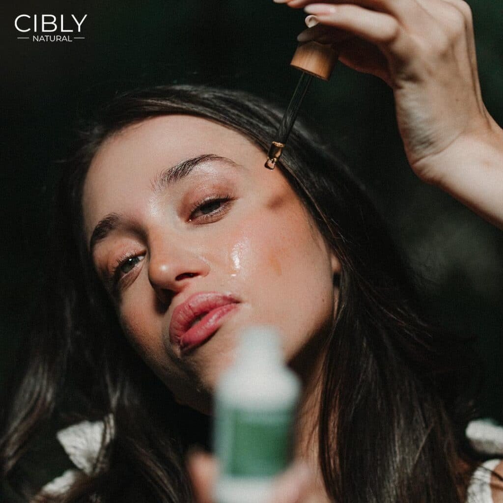 Жена нанася съставки от натурално козметично масло върху лицето си на органична козметика Cibly.