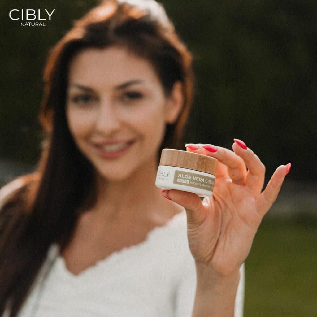 Жена с блестяща кожа държи Крем с Алое Вера от Cibly, символизирайки хидратация и сиянието на кожата.