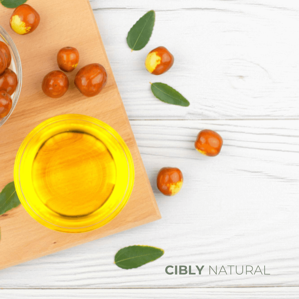 Начало 31 Златисто масло от жожоба в стъклено шише на фона на зелени листа жожоба