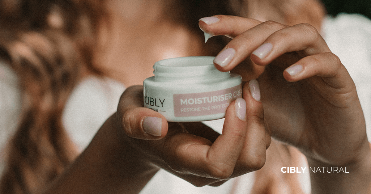 Жена нанася богат хидратиращ крем на сухата си кожа – натурална грижа за възстановяване на бариерата