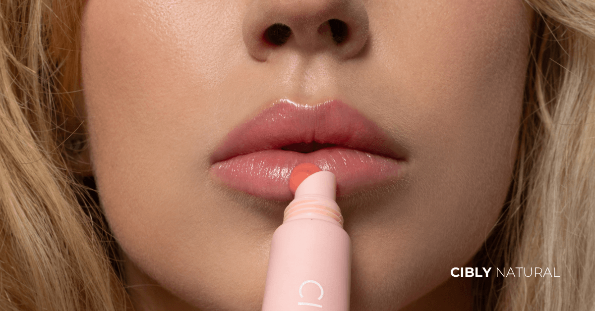 Жена нанася натурален балсам за устни с хиалуронова киселина – правилна грижа за напукани устни