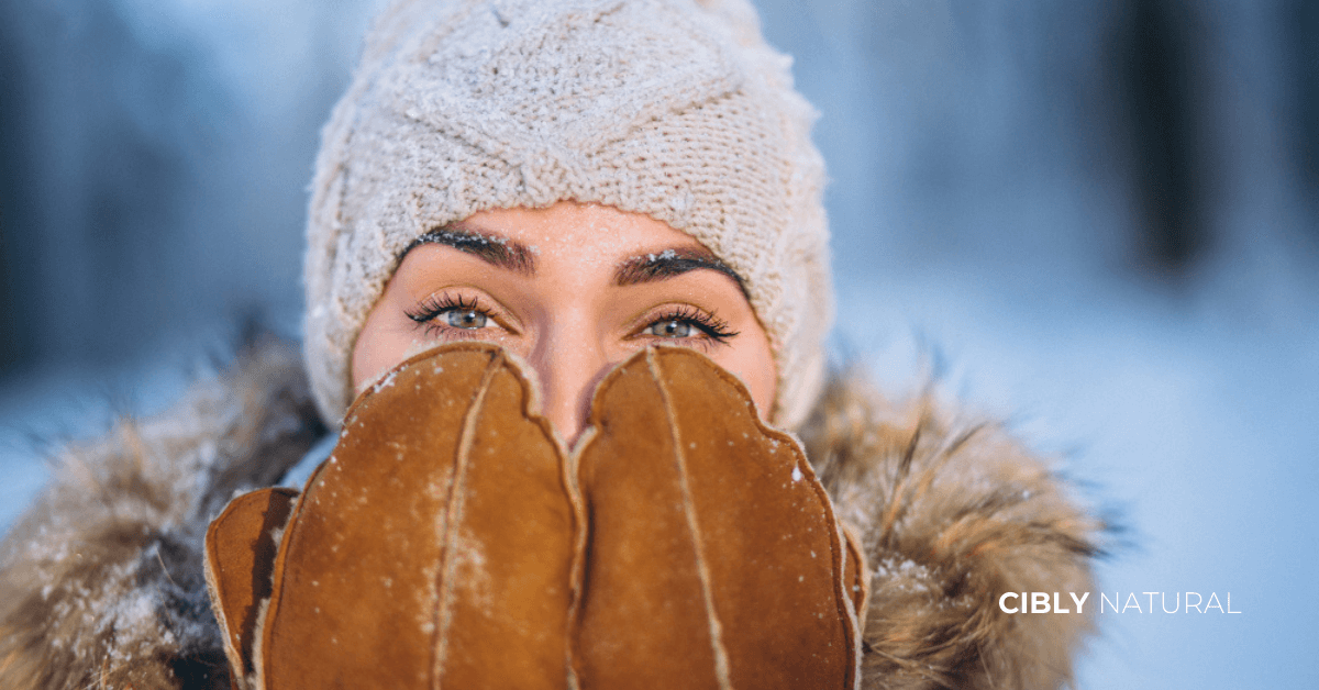 SPF през зимата – жена нанася слънцезащитен крем в снежен зимен ден