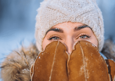 Финни линии и бръчки 77 SPF през зимата – жена нанася слънцезащитен крем в снежен зимен ден