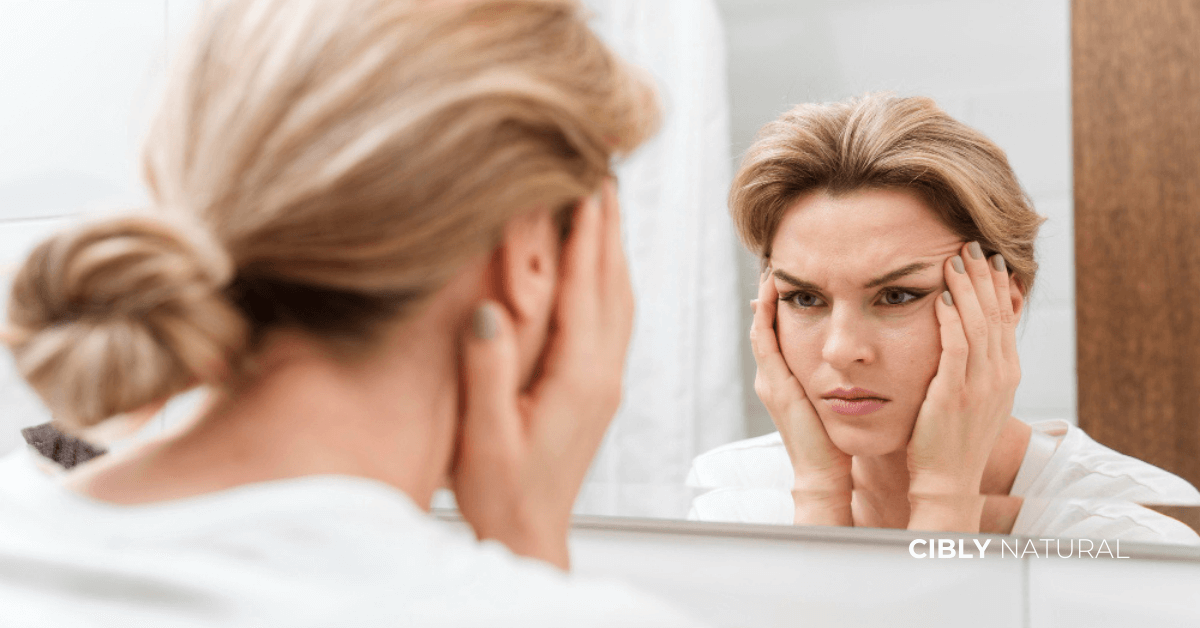 Жена проверява кожата си в огледало за признаци на дехидратация